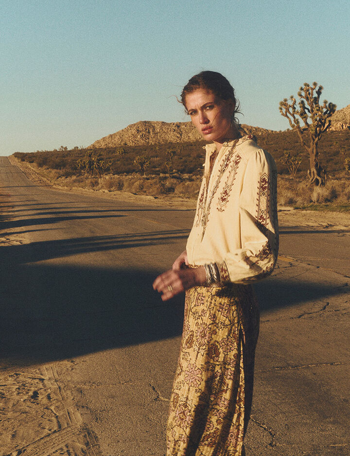 a model wearing an embroidered blouse and a floral-print skirt