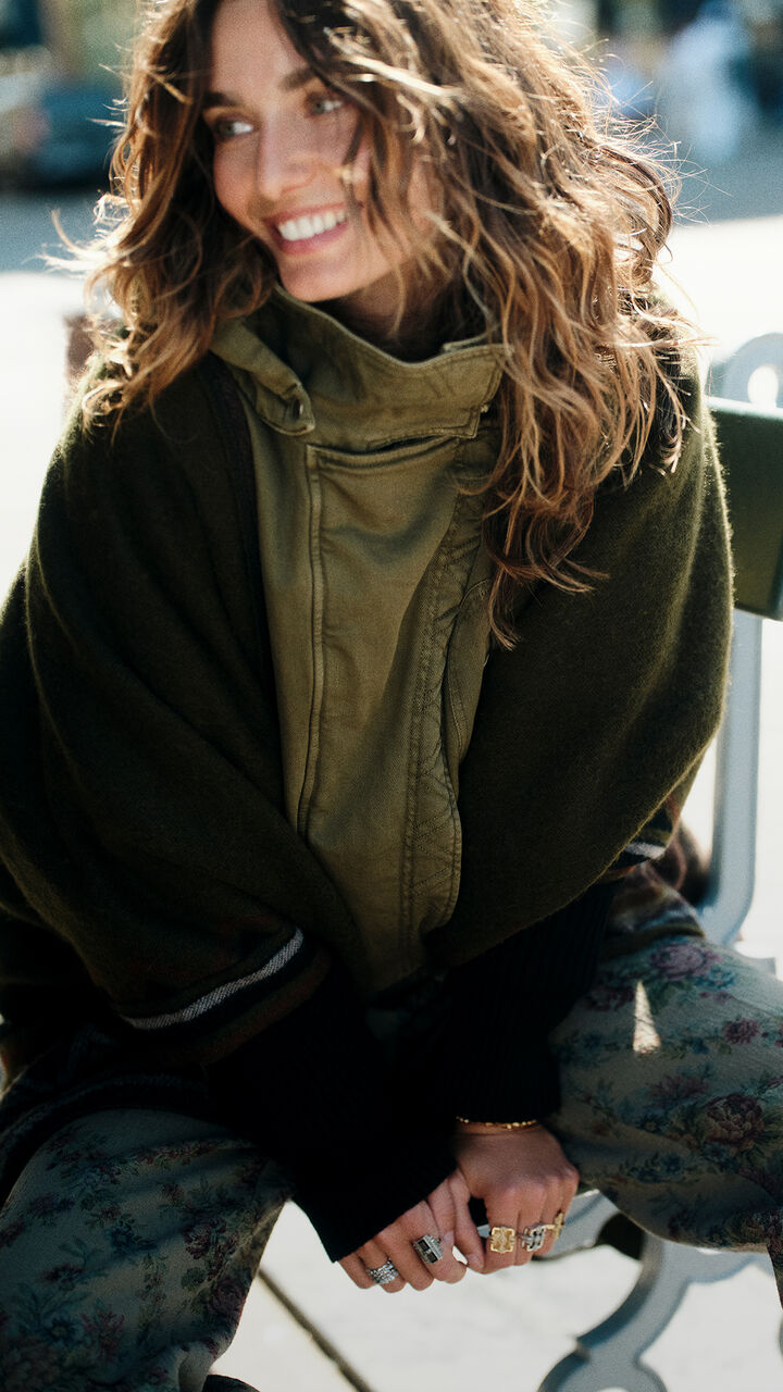 A model wearing a khaki coat, a poncho and several rings