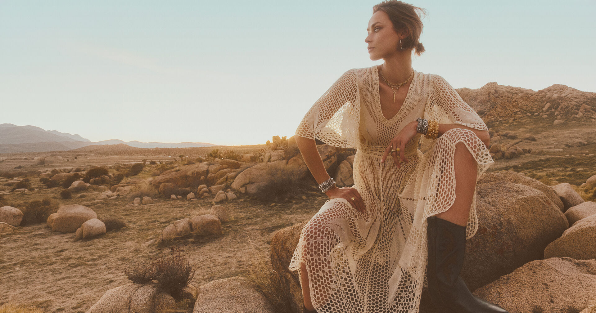 a model in the desert wearing a crocheted dress 