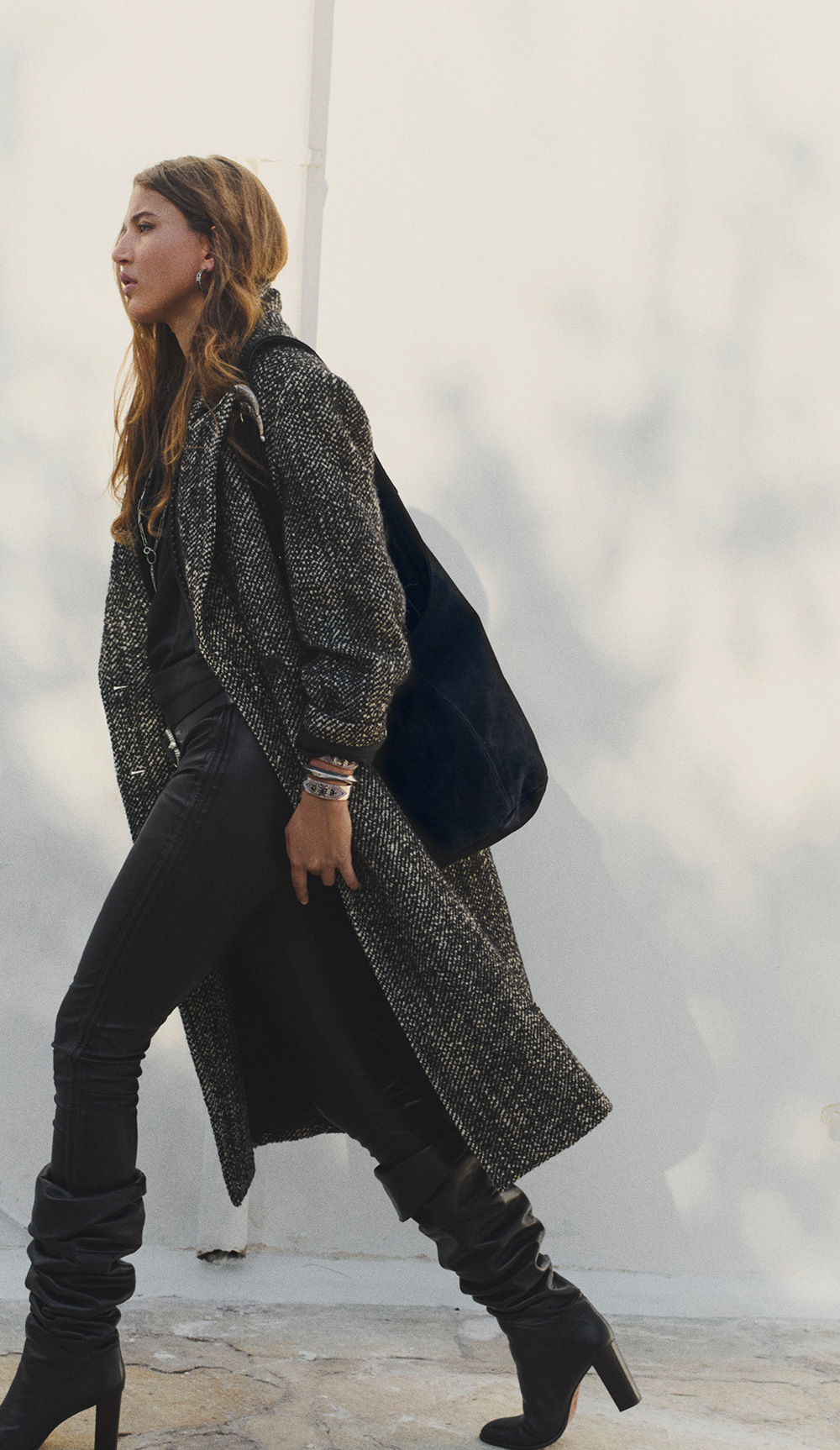 A model wearing a gray coat with black high boots