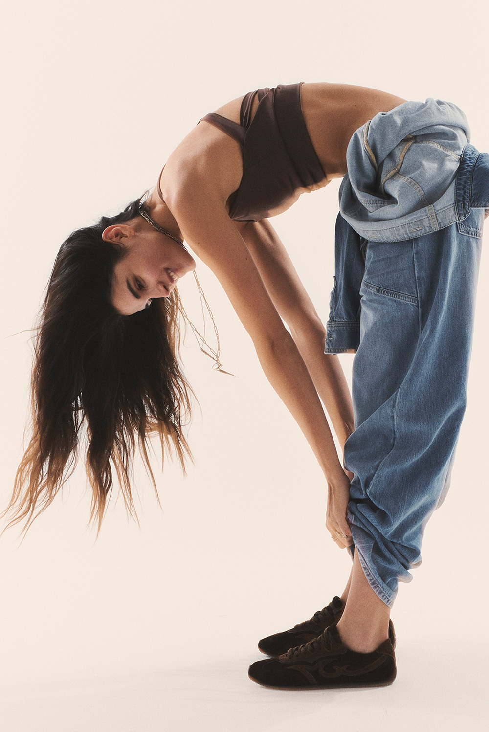 brunette model wearing a bra and blue jeans