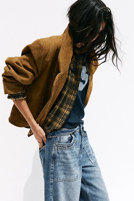 The model is wearing a camel-colored suede jacket