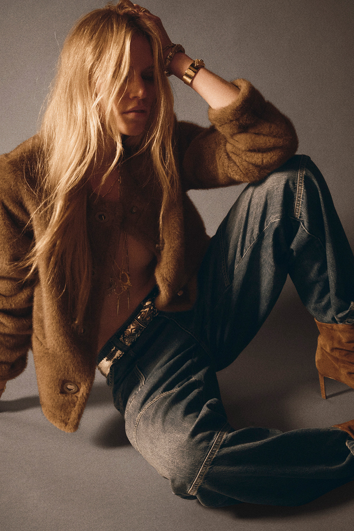 a model wearing a cognac coloured jacket with a pair of dark wash jeans 