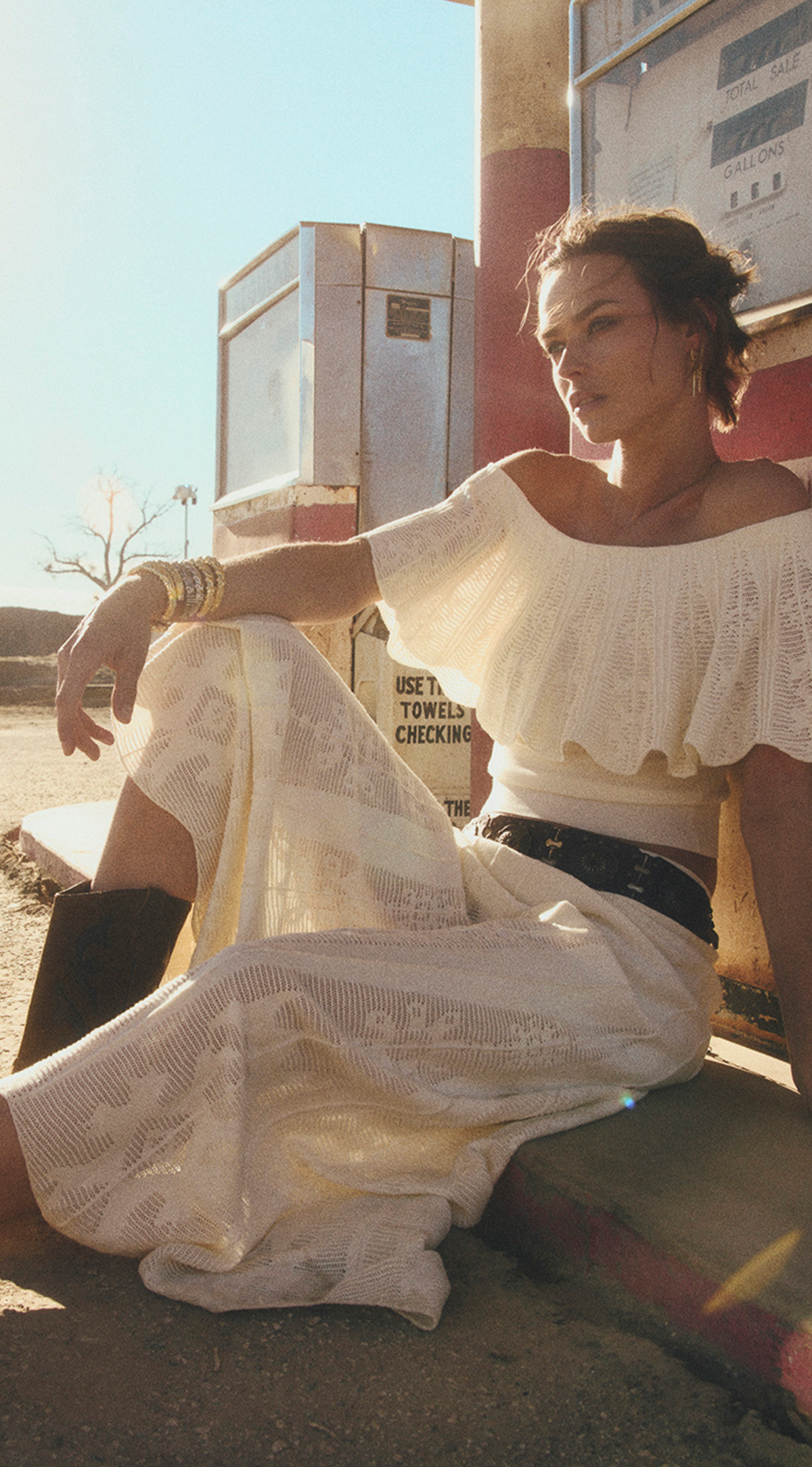 Woman in the Californian desert wearing a white off the shoulder top and a white skirt with cowboy boots