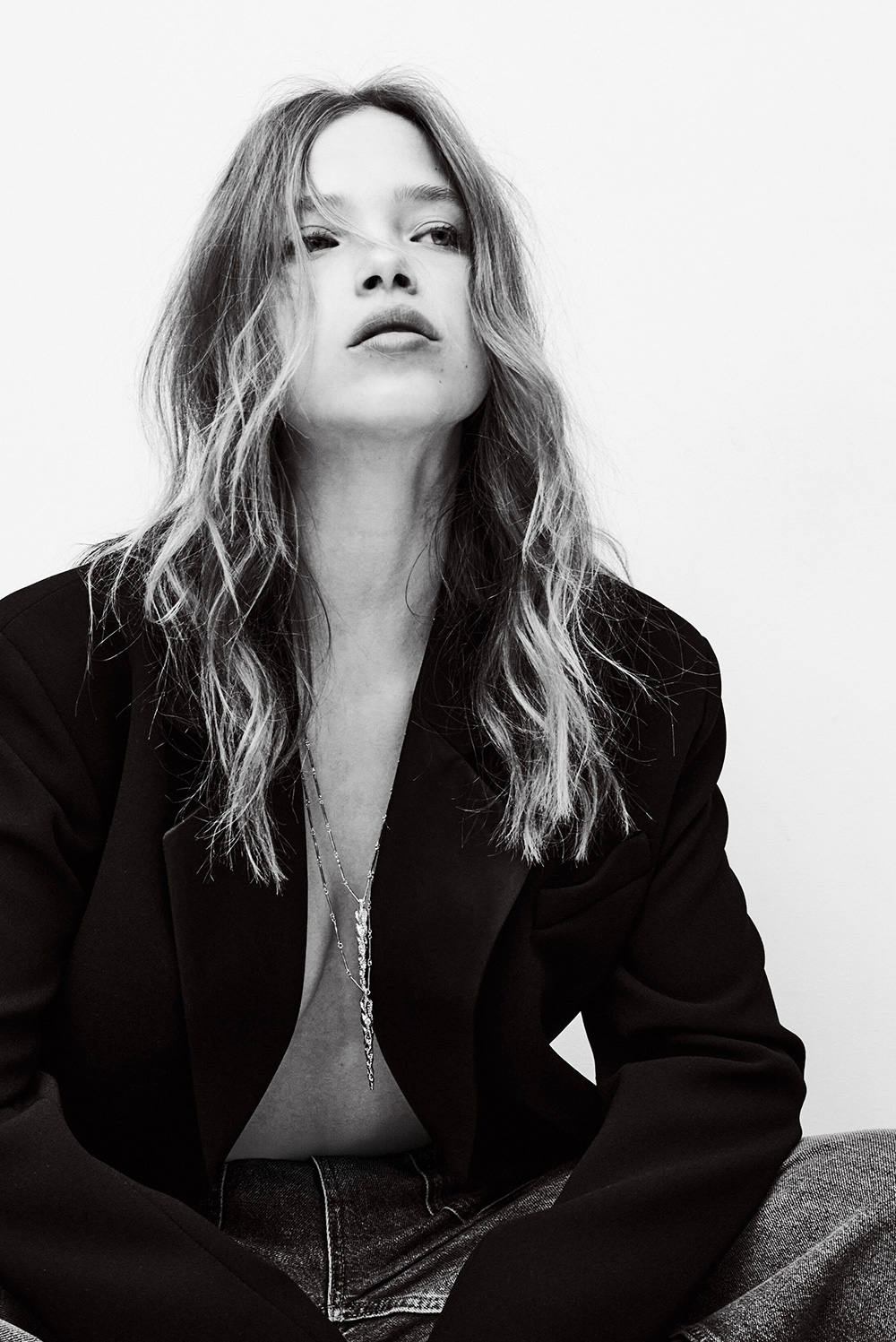 Woman wearning a black blazer layered with multiple necklaces
