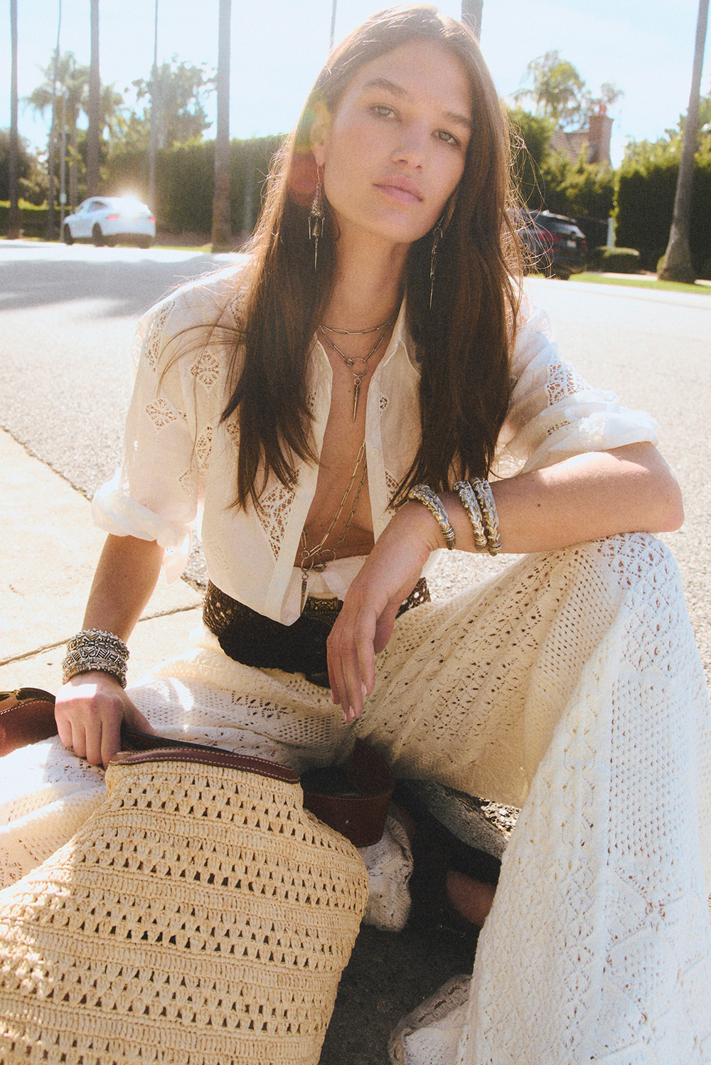 a model wearing a shirt and pants, sitting on the street 