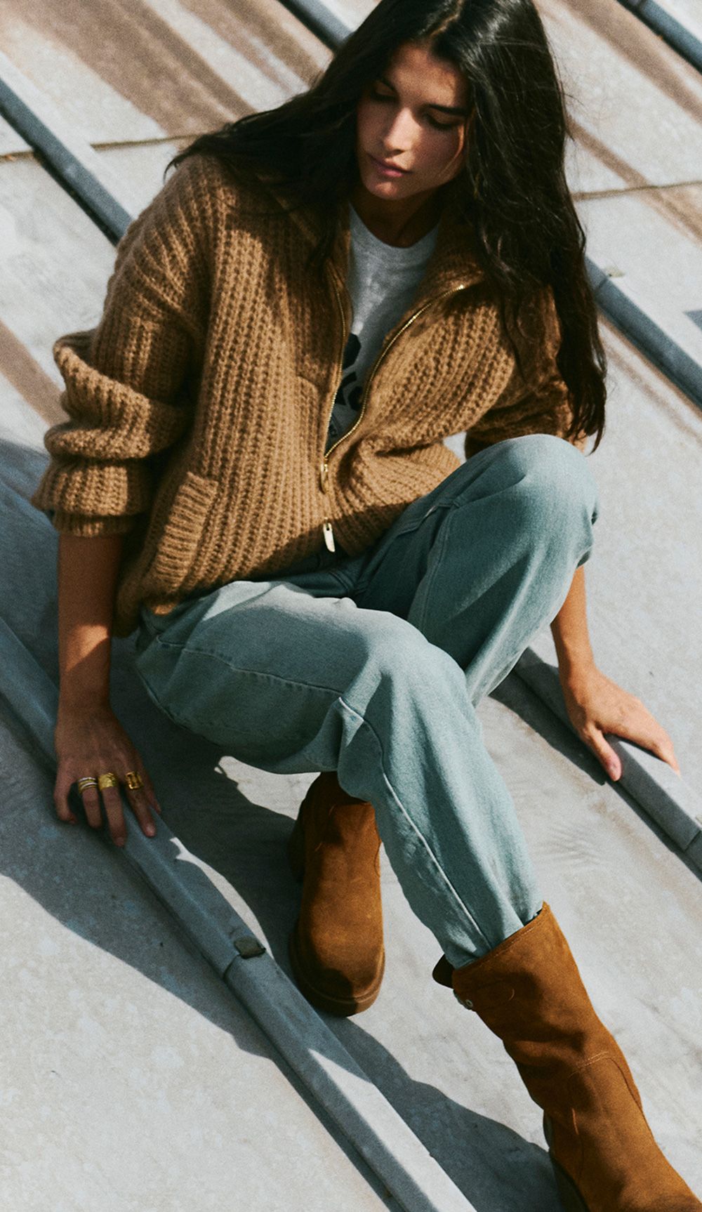 The model is wearing a knit sweater, jeans, and suede ankle boots