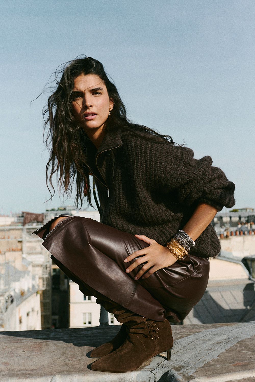 The model is wearing a knit sweater, a leather skirt, and boots