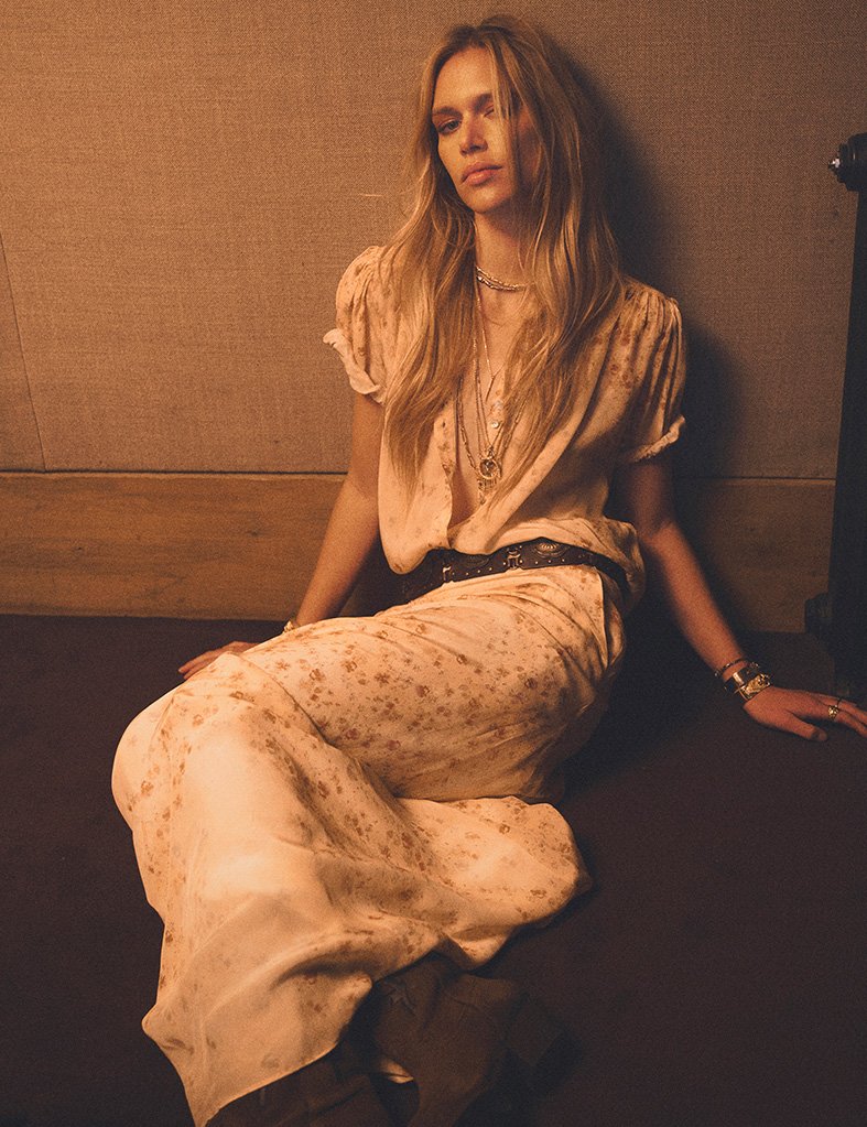 a blonde model wearing a pink dress with brown belt