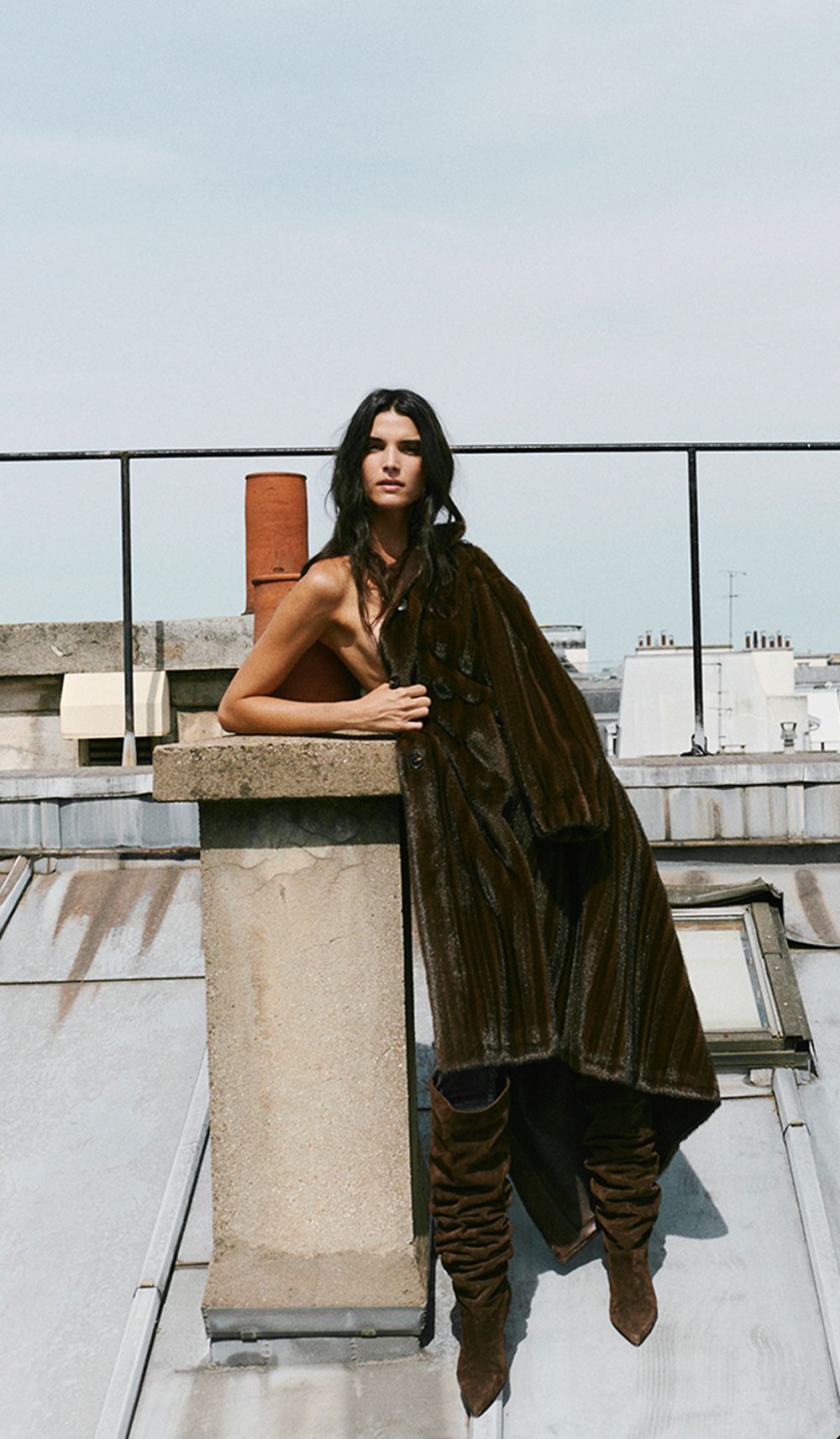 The model is wearing a long coat and boots