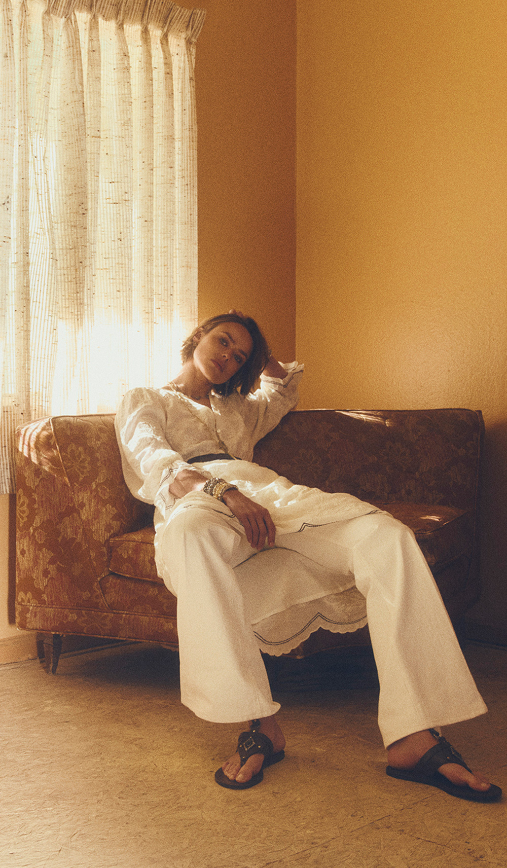 a model wearing a white outfit sitting on a chair in a hotel