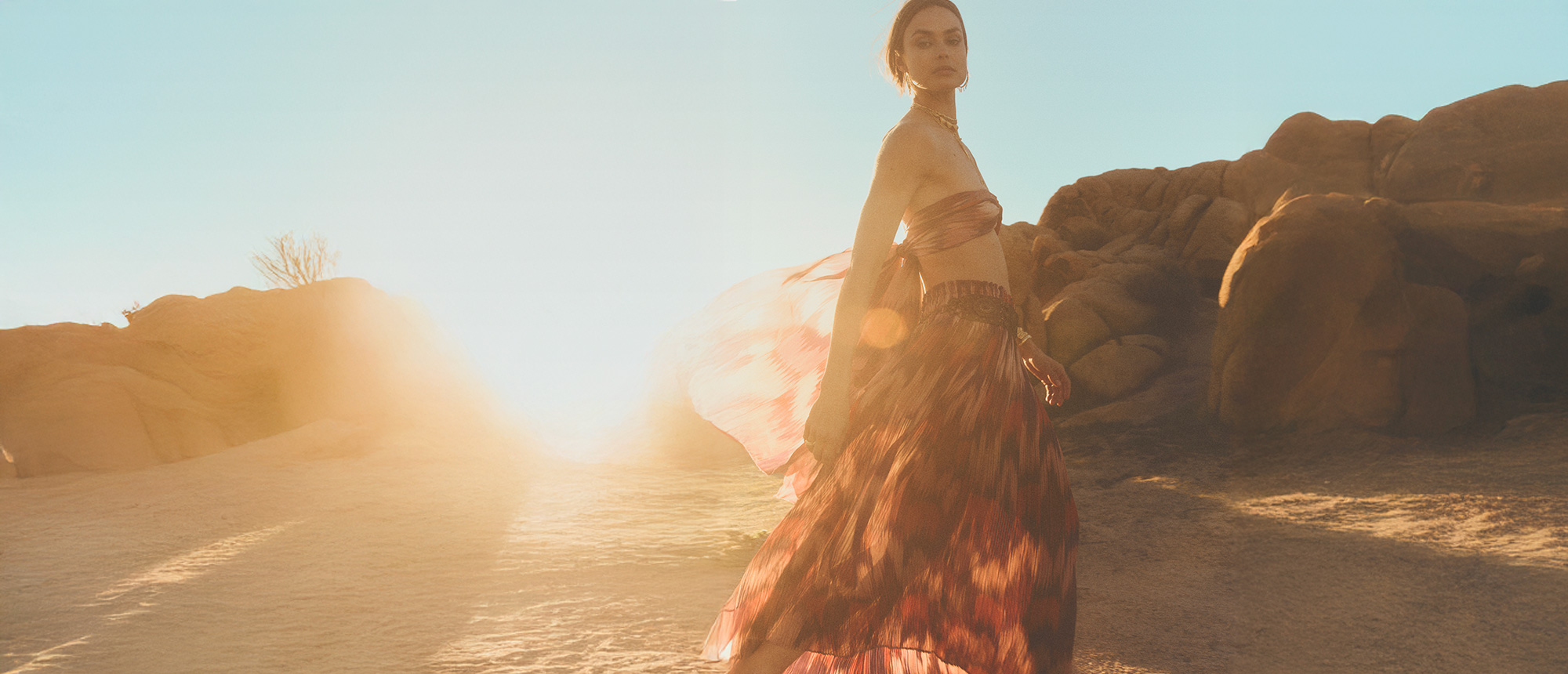 A model wearing a top and a long red printed skirt