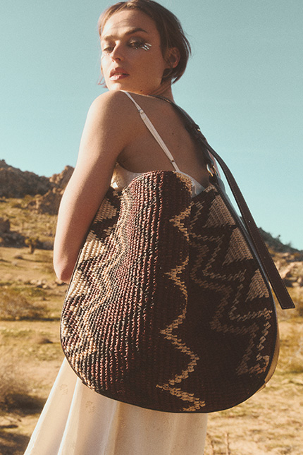 a model with a brown raffia bag