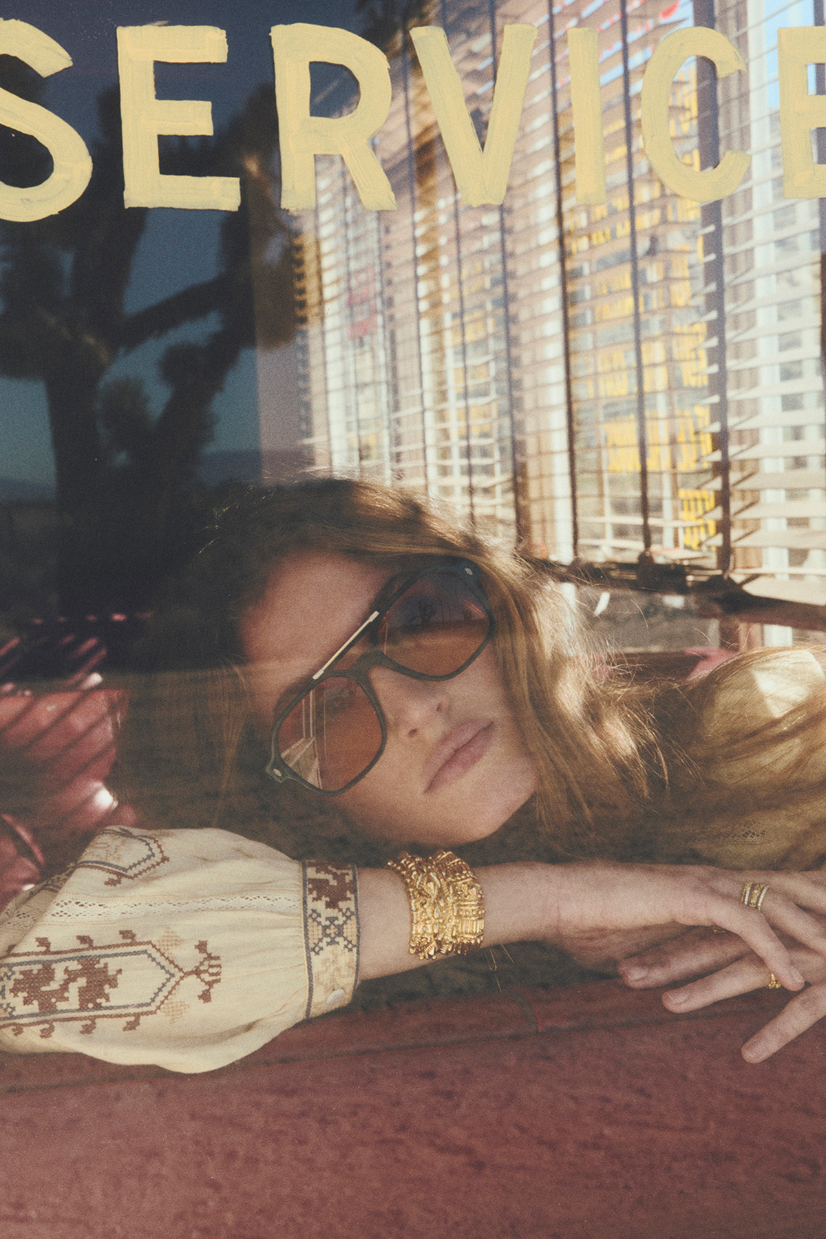 a model sitting on a dining bench wearing a shirt and sunglasses