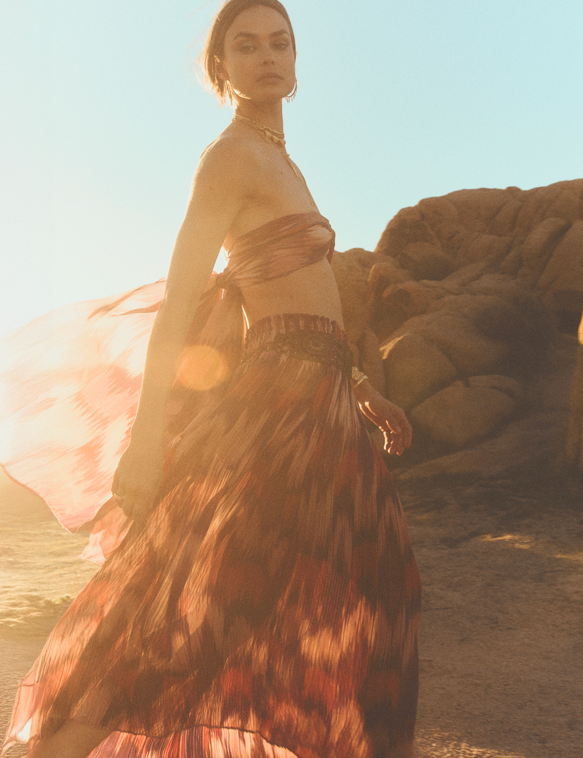 A model wearing a top and a long red printed skirt