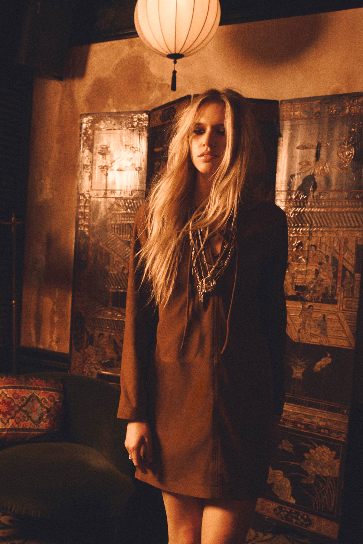 a model wearing a cognac-coloured dress with several necklaces