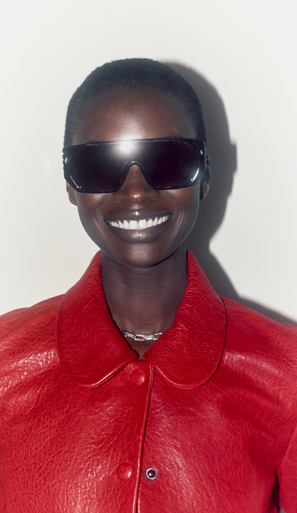 Model wearing a red leather jacket and black sunglasses