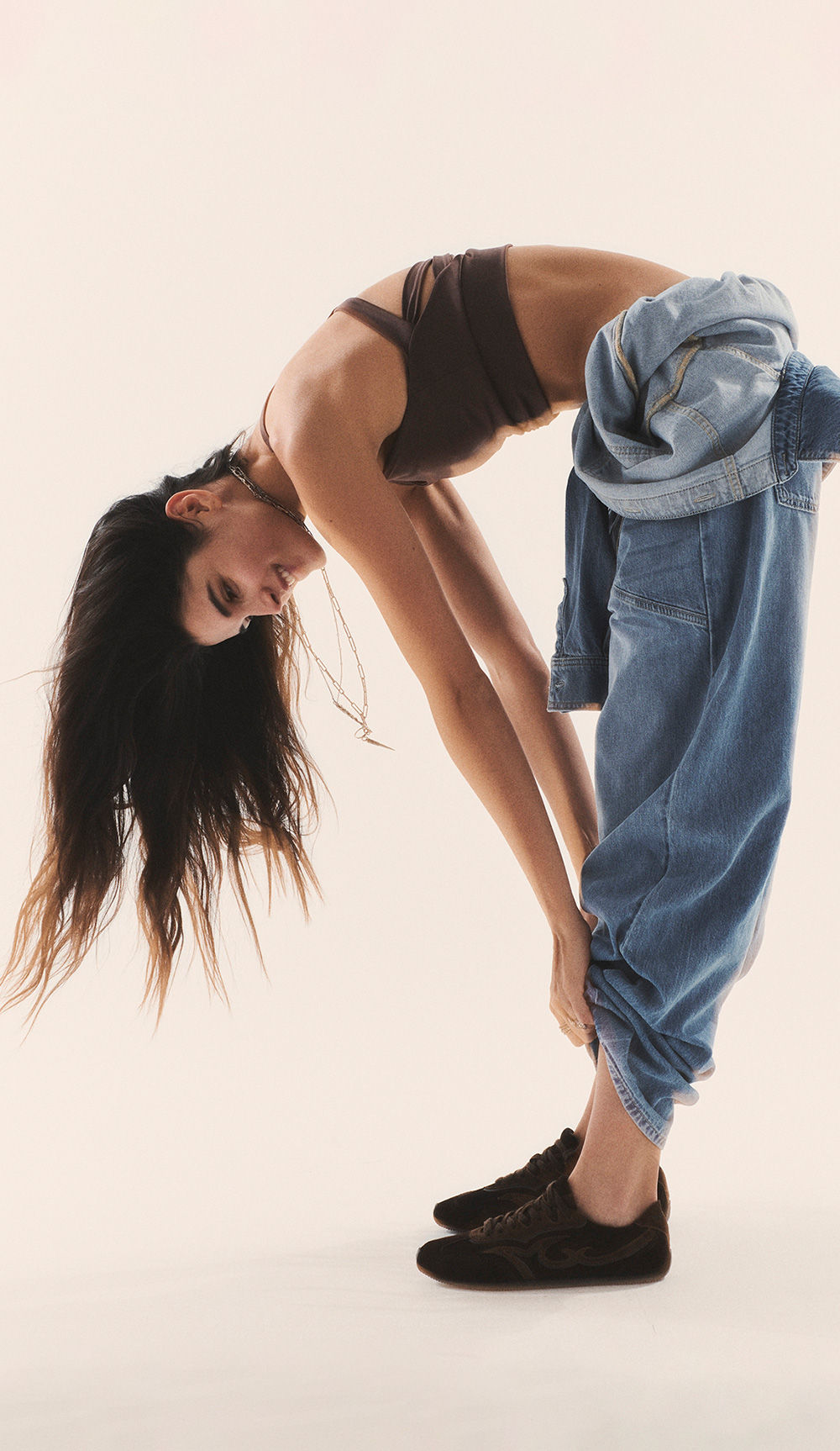 brunette model wearing a bra and blue jeans