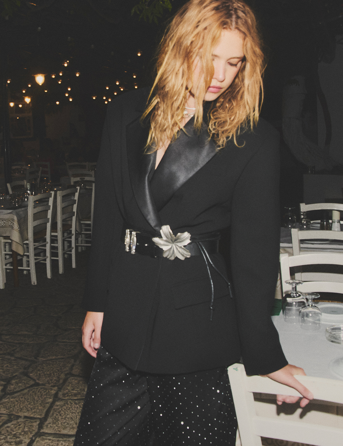 A blonde model wearing a black dress, a black blazer and a ba&sh belt
